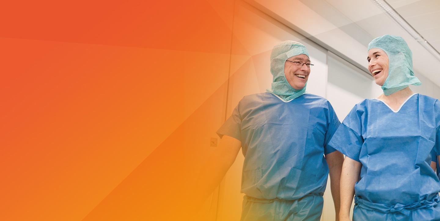 two doctors talking with each other on the hallway wearing surgical clothing