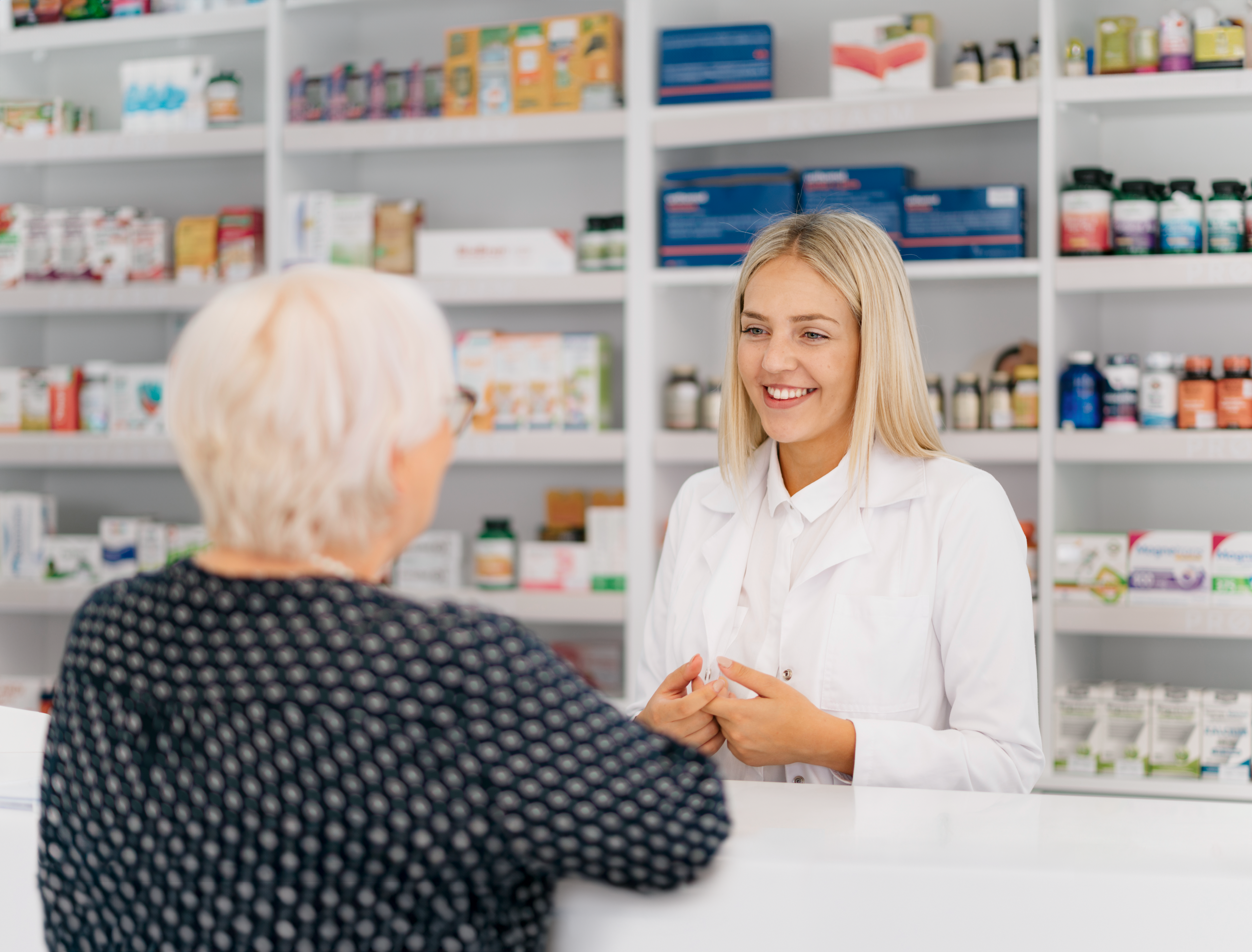  Young female pharmacist advising female senior in a pharmacy